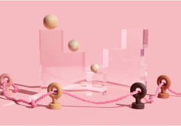 Modern abstract studio photograph featuring transparent stepped pedestals holding wooden balls behind a pink rope barrier.