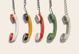 A row of five vintage telephone handsets in various colors hanging vertically against a neutral background.